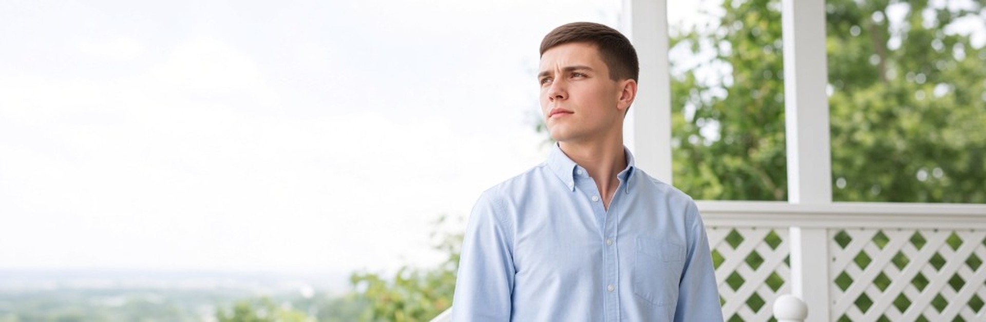 Young man standing on a porch, looking out thoughtfully
