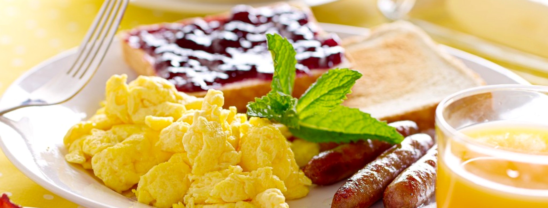 Breakfast plate with scrambled eggs, toast, sausage, and orange juice